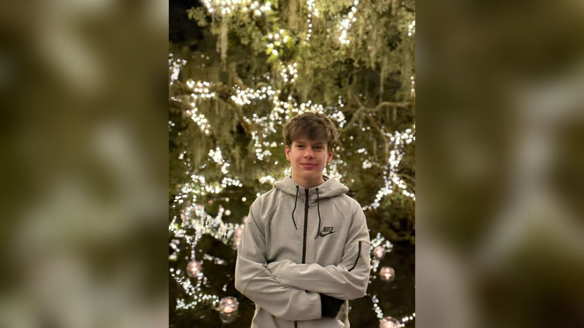 Will Parsons smiling under string lights — son of Christopher Parsons